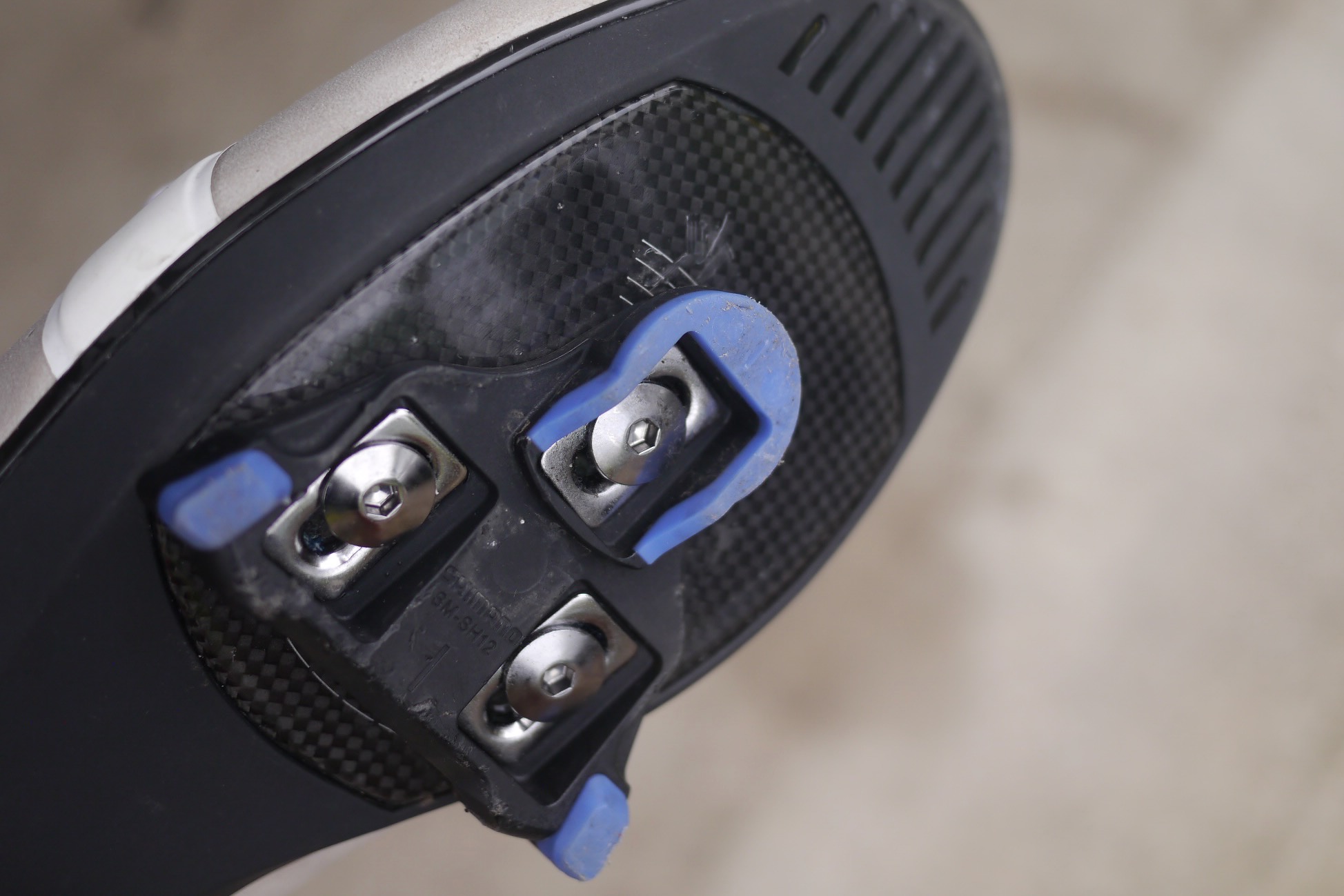 A shimano cleat mounted to the sole of a road bike shoe